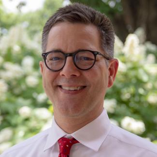 A man wearing glasses, shirt, and tie.