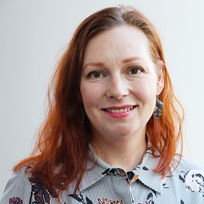 A woman with red hair and a striped print shirt.