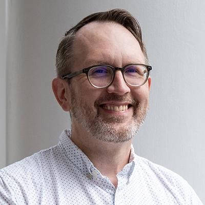 A man with glasses and a polka dot shirt.