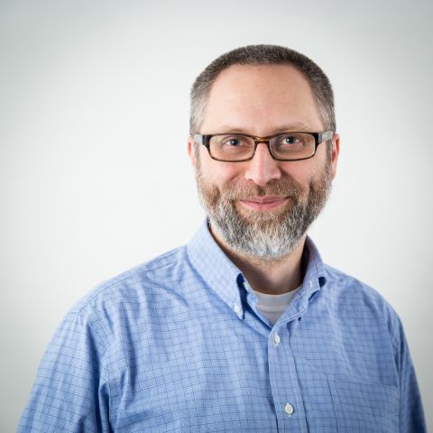 A man with glasses wearing a blue check shirt.