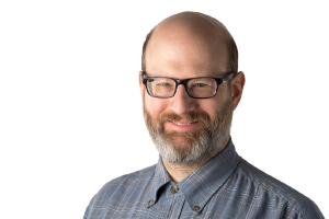 A man wearing glasses and a dark plaid shirt.