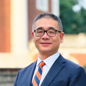 Outdoor portrait of a smiling man in glasses.
